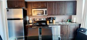 a kitchen with wooden cabinets and stainless steel appliances at Lakefront living Downtown Toronto - Free Parking and Gym in Toronto