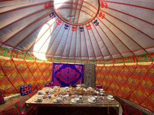 a table in a yurt with plates and cups on it at Center guesthouse in Kochkorka