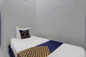 a bed with a yellow and blue pillow on it at SPOT ON 92828 Galih Kost 1 Syariah in Grobogan