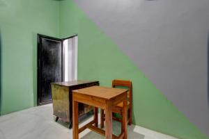 a wooden table and a chair next to a green wall at SPOT ON 92828 Galih Kost 1 Syariah in Grobogan
