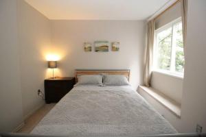 a white bedroom with a bed and a window at Kitsilano Beach Executive Condo in Vancouver