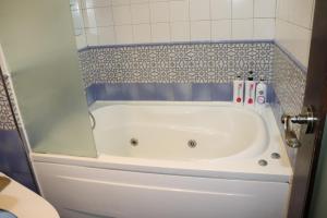 a bath tub in a bathroom with a tile wall at Hotel Marigold in Incheon