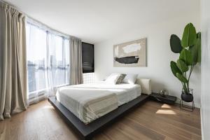 um quarto branco com uma cama e uma grande janela em Amazing Location - 2BDRM/2BATH - right on Robson em Vancouver