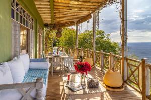a porch with a couch and tables on a balcony at Arcadia Cliff House in Kwale