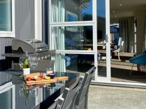a glass table with a plate of food and a bottle of wine at Relax, Refresh, Recharge in Twizel