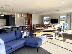 a living room with a blue couch and a dining room at Relax, Refresh, Recharge in Twizel