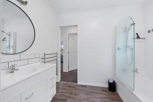 a white bathroom with a shower and a sink at Lakeside Haven - Taupo Holiday Home in Taupo +17 photos