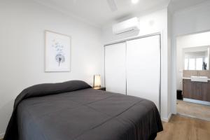 1 dormitorio con 1 cama y puerta corredera de cristal en Lake Poco Apartments, en Mackay