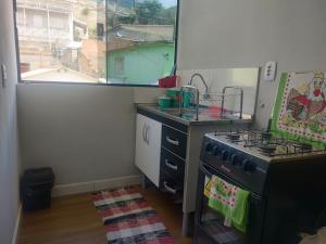 eine Küche mit einem Herd, einem Waschbecken und einem Fenster in der Unterkunft suites montanha das letras in São Thomé das Letras