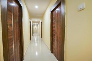 un largo pasillo con puertas de madera y un pasillo con azulejos blancos en OYO R Square Stay Near LB Nagar Metro, en Surūrnagar