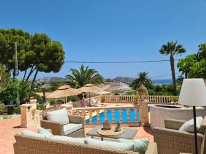 a patio with wicker furniture and a balcony with palm trees at Casa Wens Bénimeit in Moraira
