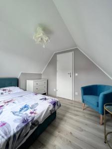 a bedroom with a bed and a blue chair at Polanki 22 in Łeba