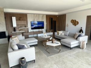 ein Wohnzimmer mit weißen Sofas und einem Fernseher in der Unterkunft villa vue mer « golf St Tropez » les issambres in Les Issambres
