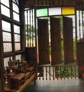 een kamer met ramen en houten tafels en banken bij Baan Mali Lampang Homestay in Lampang