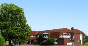 un bâtiment en briques rouges avec un arbre devant lui dans l'établissement Hotel Sembziner Hof, à Klink