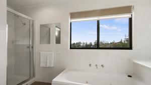 Un baño blanco con bañera y ventana. en Cunninghame Views, en Lakes Entrance 14 fotos más