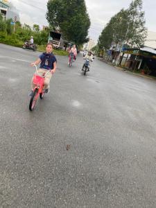 a group of people riding bikes down a street at Mekong Farmstay CanTho - C.R Floating Market in Can Tho