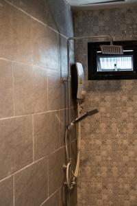 y baño con ducha y pared de azulejos. en We World Boutique Haatyai en Hat Yai