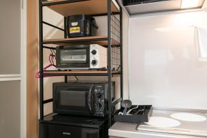 a kitchen with a microwave and a tv and a shelf at Ferio101 in Tokyo