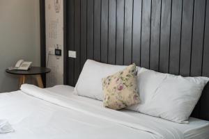 a white bed with two pillows and a telephone at We World Boutique Haatyai in Hat Yai