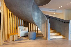 a lobby with a staircase with a chair and a table at Crowne Plaza - Marseille Le Dôme in Marseille