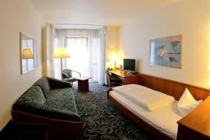 カールスルーエにあるアルファ ホテル スーペリアのベッド、ソファ、デスクが備わるホテルルームです。