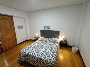 a bedroom with a bed with a black and white blanket at Apartamento familiar gran Bilbao in Basauri