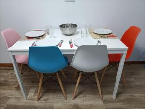 a table with three chairs and a white table with plates at Apartamento familiar gran Bilbao in Basauri