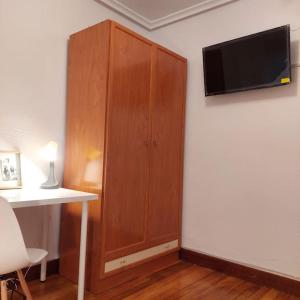 a wooden cabinet with a television on a wall at Apartamento familiar gran Bilbao in Basauri