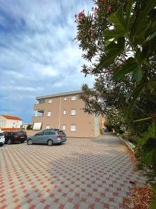 a parking lot with cars parked in front of a building at Apartment Mario, Novalja in Novalja