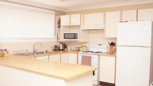 a kitchen with white cabinets and a white refrigerator at Pet Friendly Cockatoo Corner in Armidale