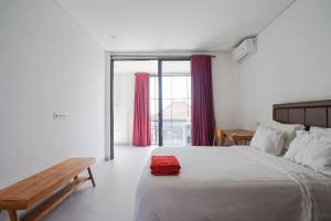 a bedroom with a large bed and a wooden bench at Margarita Apartment and Coworking Canggu in Canggu