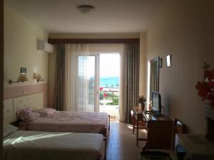 a bedroom with two beds and a desk and a window at Kitesurf Paradise Studios in Theologos