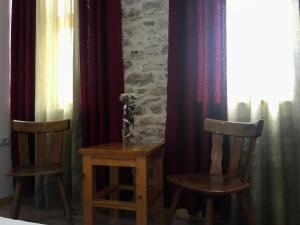 two chairs and a table in a room with curtains at Vila ERI in Gjirokastër