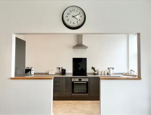 a kitchen with a clock on the wall at Spacious Apartment~Parking~Close to Seafront in Penzance +4 photos