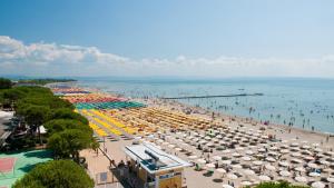 a beach with umbrellas and people in the water at apartment GiòHome in Grado
