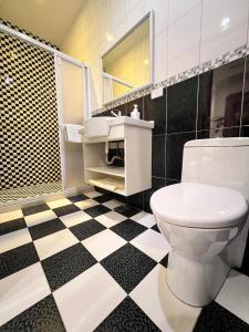 uma casa de banho com um WC e um piso xadrez preto e branco em Kaishen Hotel em Taitung City