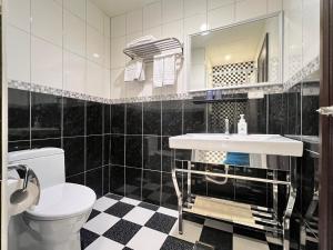 un bagno bianco e nero con lavandino e servizi igienici di Kaishen Hotel a Città di Taitung