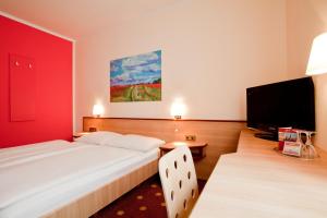 a bedroom with a large bed and a flat screen tv at Hotel die kleine Sonne Rostock in Rostock