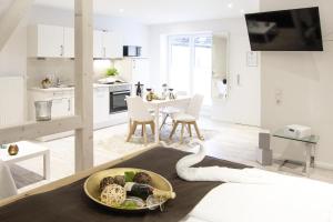 eine weiße Küche und ein Wohnzimmer mit einer Schlange auf dem Boden in der Unterkunft Schwalbennest in Flensburg