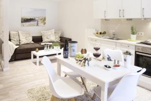 cocina y sala de estar con mesa blanca y sillas en Schwalbennest en Flensburg
