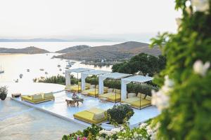 a resort with a pool with yellow chairs and a beach at Aigis Suites Kea in Vourkari