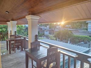 a patio with tables and chairs on a porch at Villa KhounSok Sunset in Luang Prabang