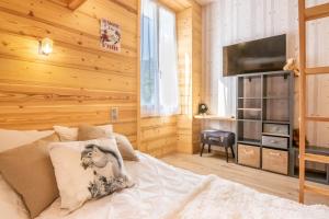 Schlafzimmer mit Holzwänden und einem Bett mit TV in der Unterkunft le clos grillet in La Chambre