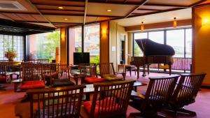 een kamer met een piano en tafels en stoelen bij Seaside Hotel Mimatsu Ooetei in Beppu