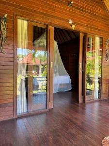 een slaapkamer met glazen schuifdeuren en een bed bij Maharatu Villa Lembongan in Nusa Lembongan