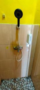 a bathroom with a shower with a hair dryer on the wall at Ruteng Hostel in Ruteng
