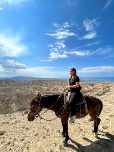 una mujer montando un caballo en la cima de una colina en Yurt camp Sonun en Bokonbayevo
