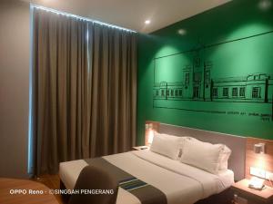 a bedroom with a bed with a green wall at Singgah Pengerang Hotel in Pengerang