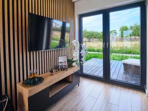 a living room with a television and a sliding glass door at Apartamenty Marinera in Łeba
